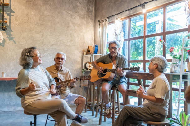 A group of asian active seniors playing guitars during their music group session.