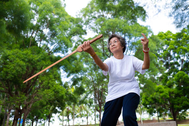 Asian senior woman working out with a wooden sword