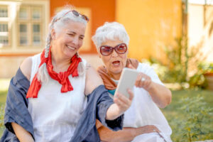 two active women adults having fun on a phone outdoors