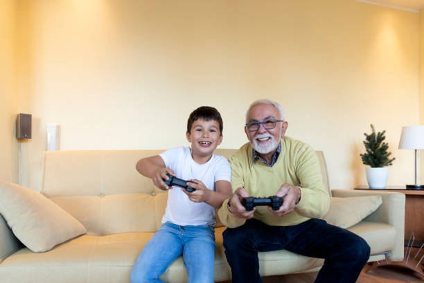 An older man playing video games with his grandson.