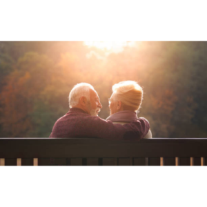 An elder couple sitting together facing the sunset.