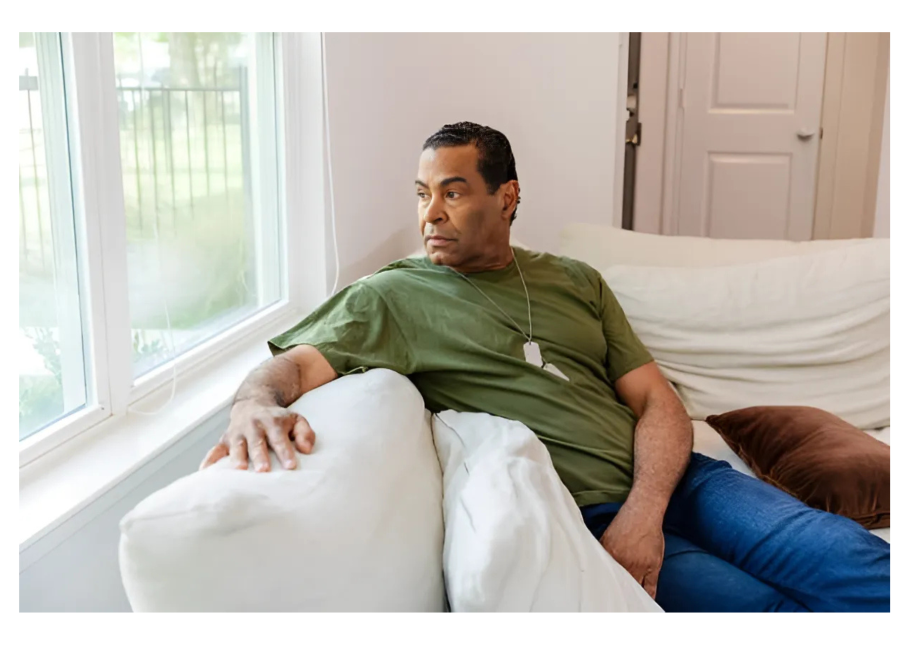 A veteran sitting on the corner of the couch while overlooking outside the window