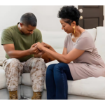 A woman consoling while holding the hands of a man who is experiencing PTSD.