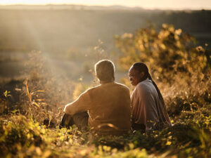 A couple of independent living seniors enjoying the sunset on a hill.