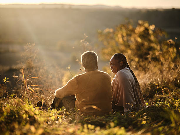 A couple of independent living seniors enjoying the sunset on a hill.